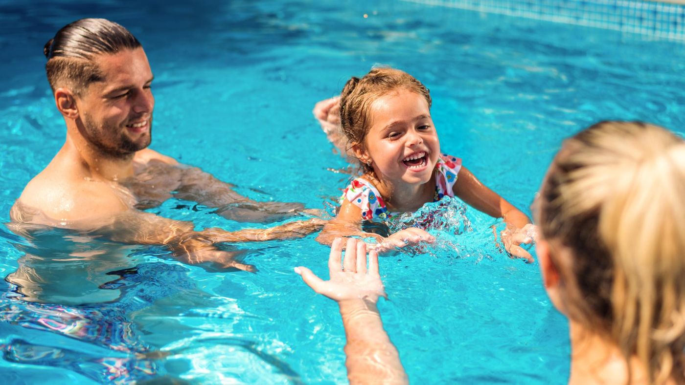 Parents helping their child swim in pool.jpg