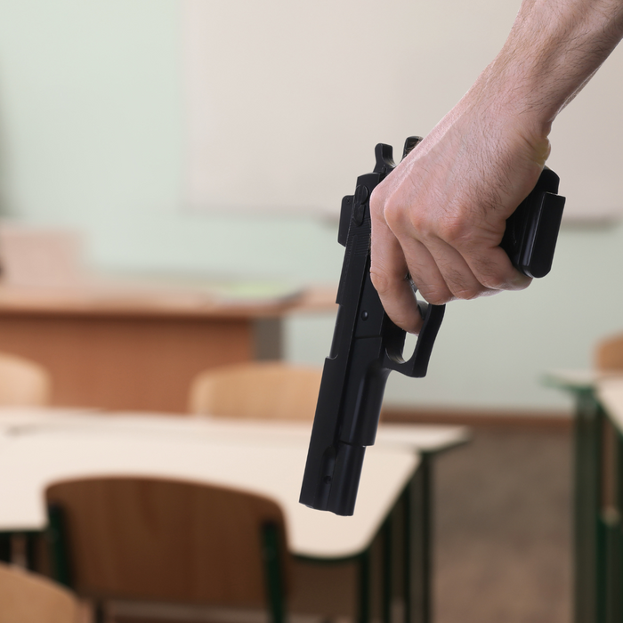 A  person with a gun in an empty classroom