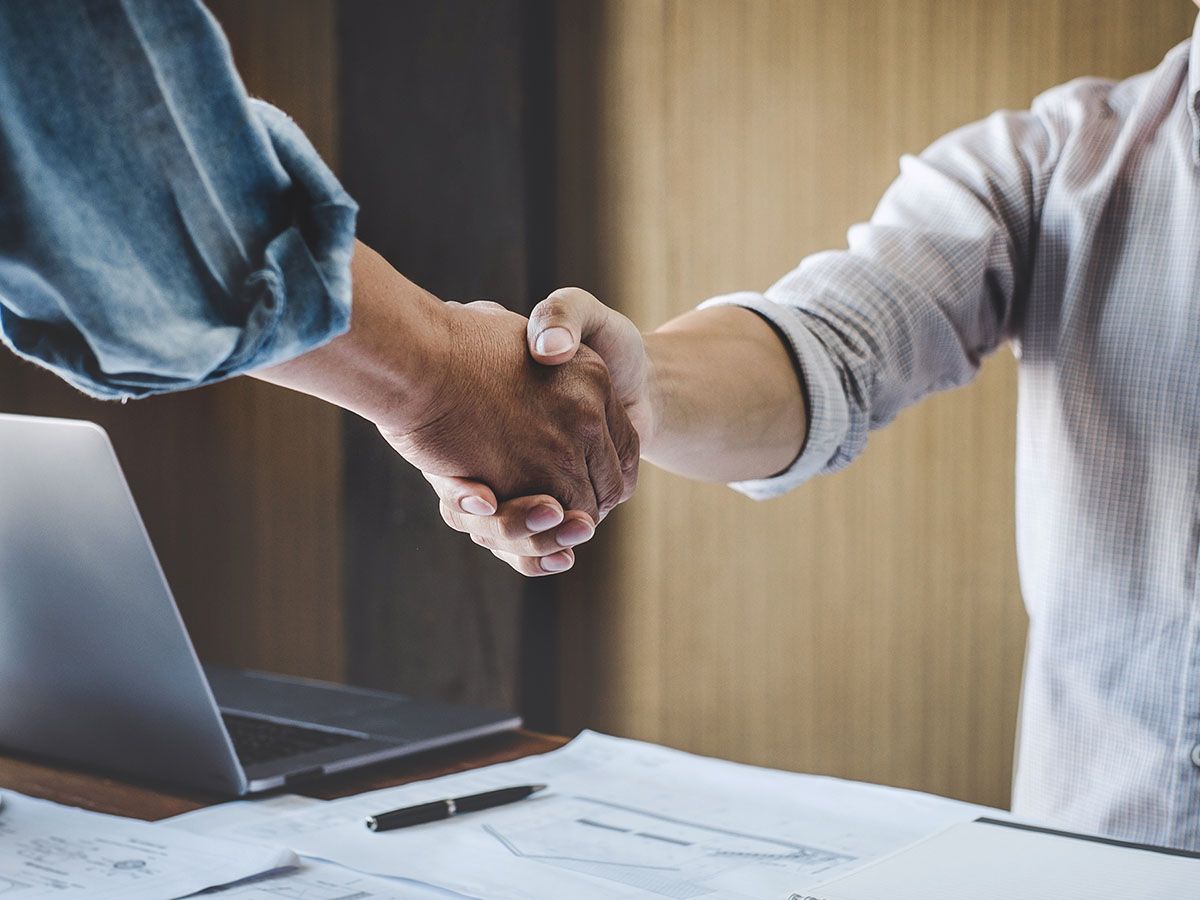 Two people handshake at a desk