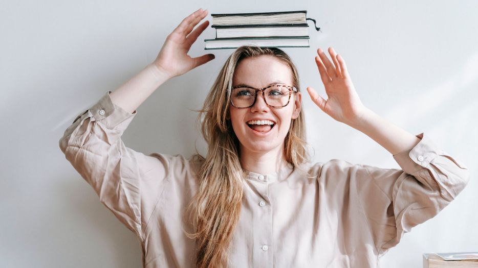 a teen with glasses and books on her head The Benefits of Routine Eye Exams for Students Hero.jpg