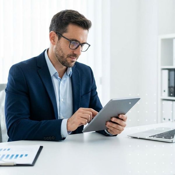 Business professional reviewing data analytics and IT compliance reporting charts on a tablet.