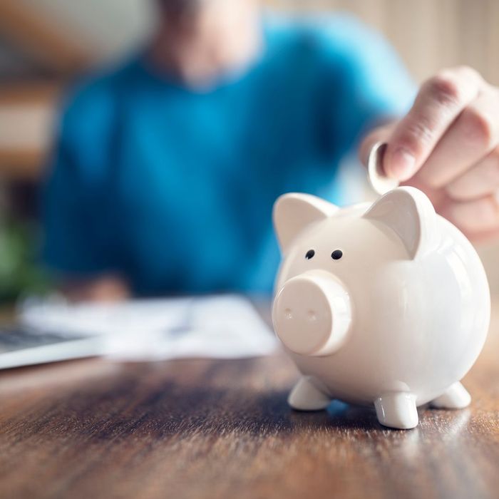 image of a person at a desk placing a coin in a piggy bank