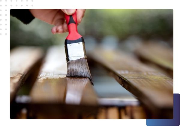 someone staining a fence with a paint brush