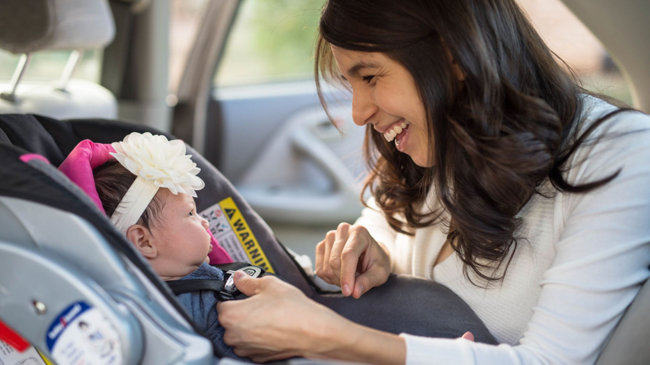 mother smiling at infant in car seat