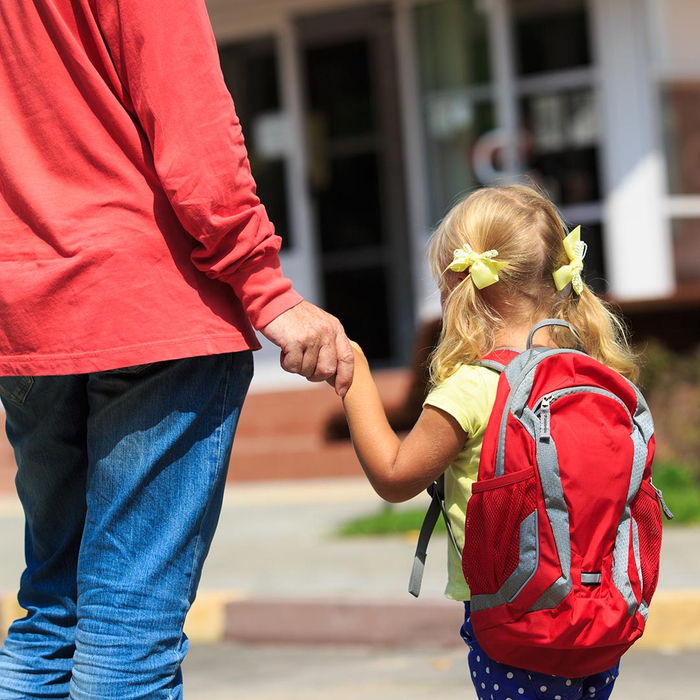 father holding daughter's hand and walking her towards school