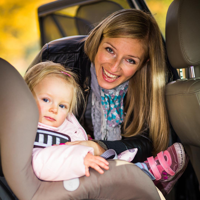 mom getting her daughter out of a car seat