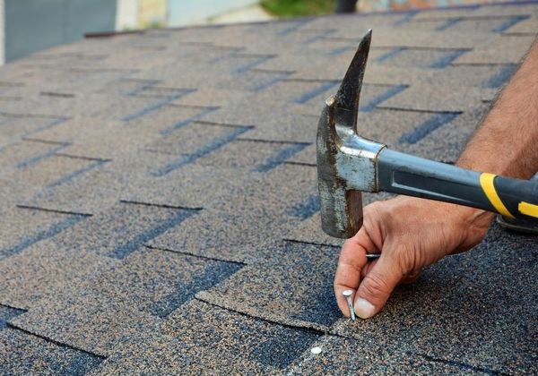 roofer hammering nail into shingles