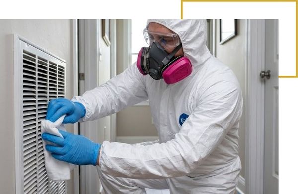 Hazmat technician wiping down a home air vent