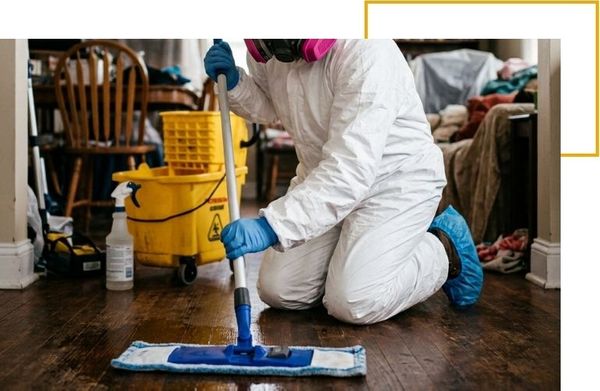 Technician in hazmat suit mopping floor during biohazard cleanup