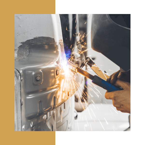 a person in safety gear welding a car