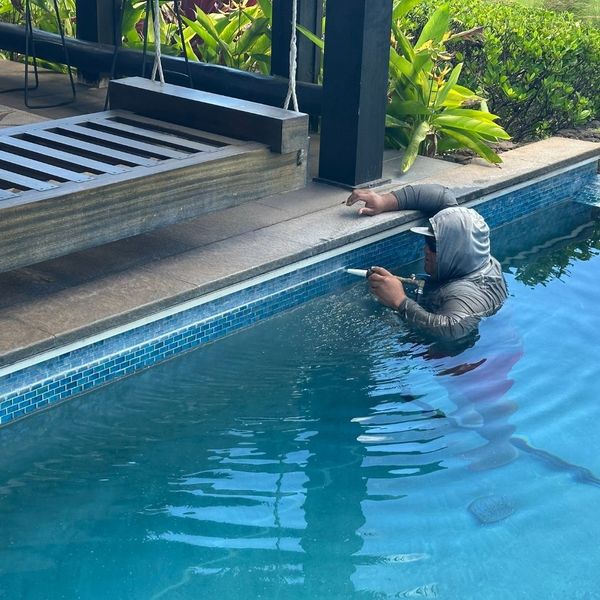 pool technician fixing the tile on a pool