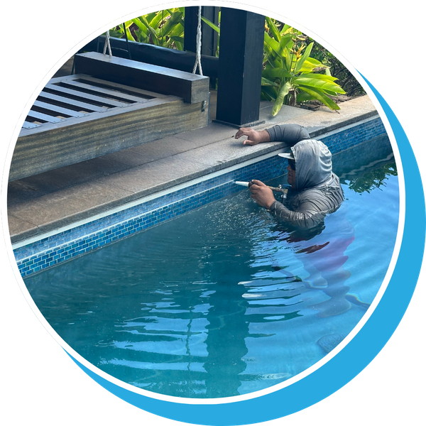 Man caulking and cleaning pool tiles