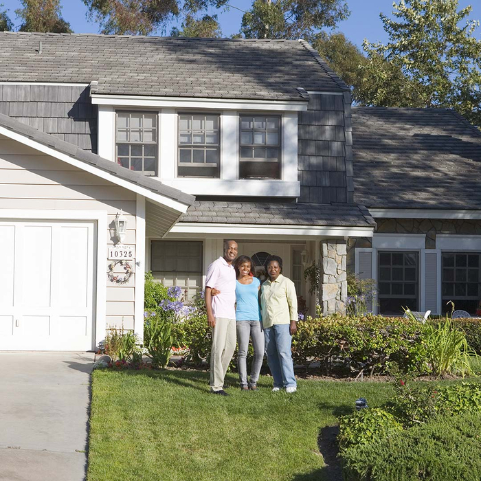 Family smiling in front of their house