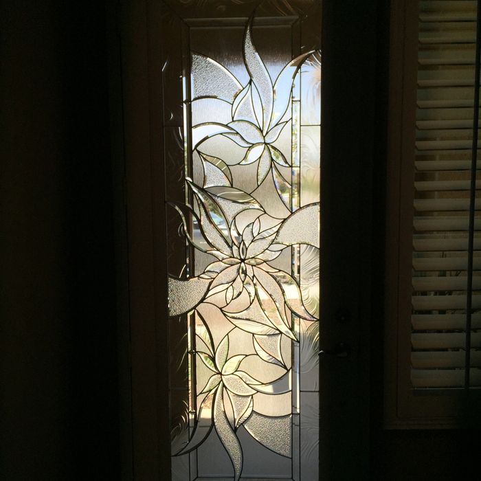 A close-up interior view of a glass door insert featuring a large, artistic etched flower design with textured glass petals.