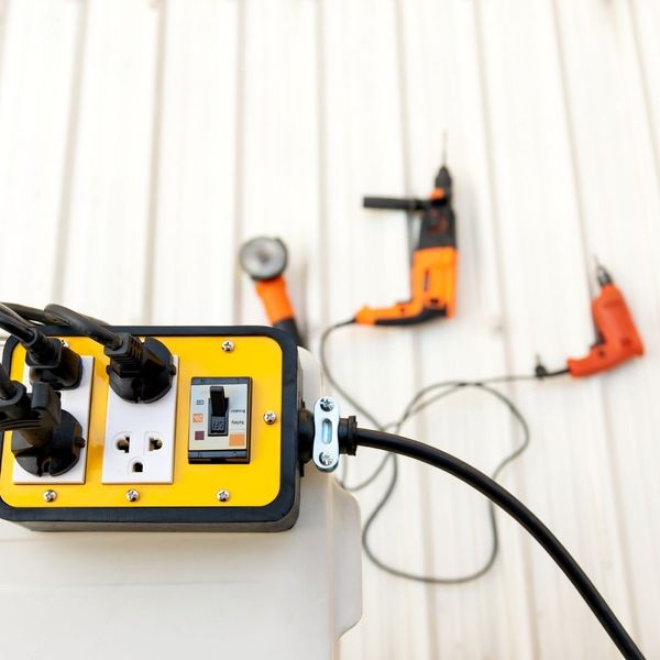 High-power industrial tools are plugged into an outdoor yellow power distribution box.