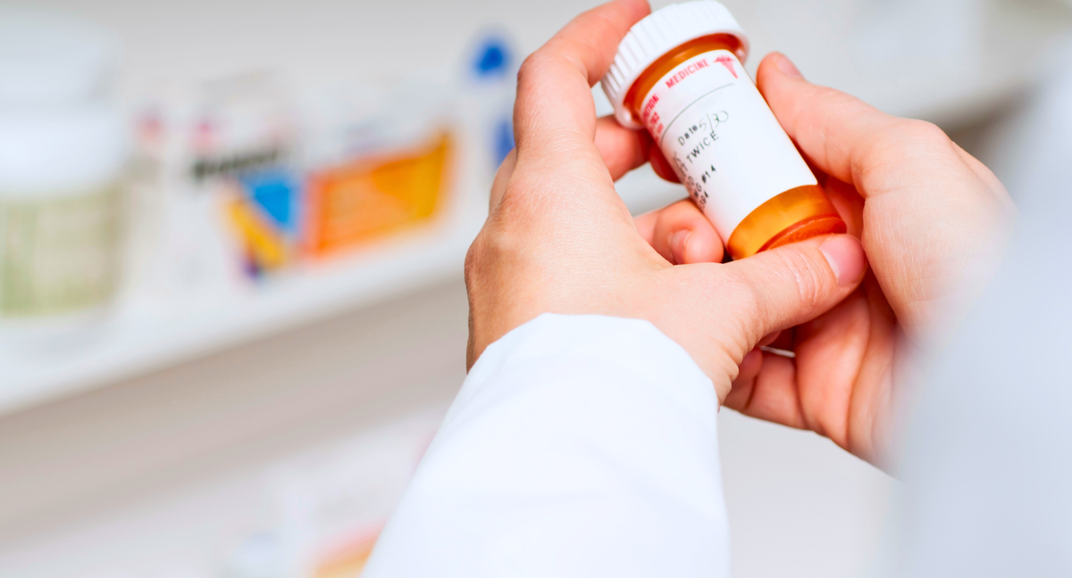 Pharmacist holding a prescription bottle.