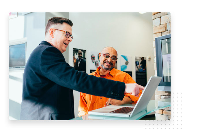 two men discussing presentation on laptop