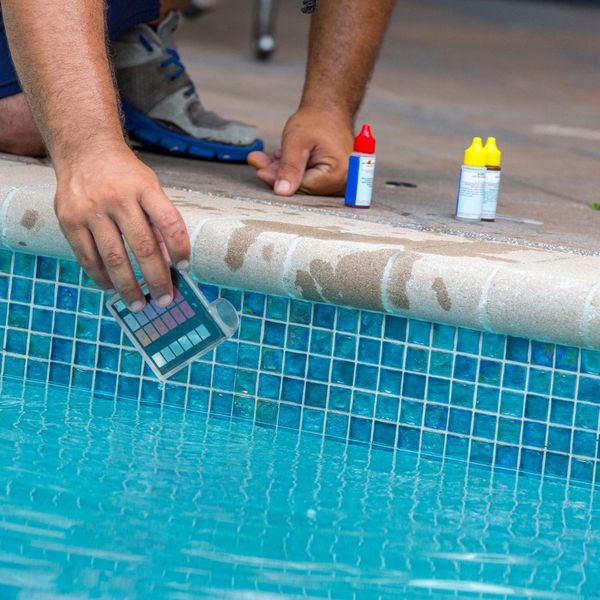 Person testing chemicals in a pool. 