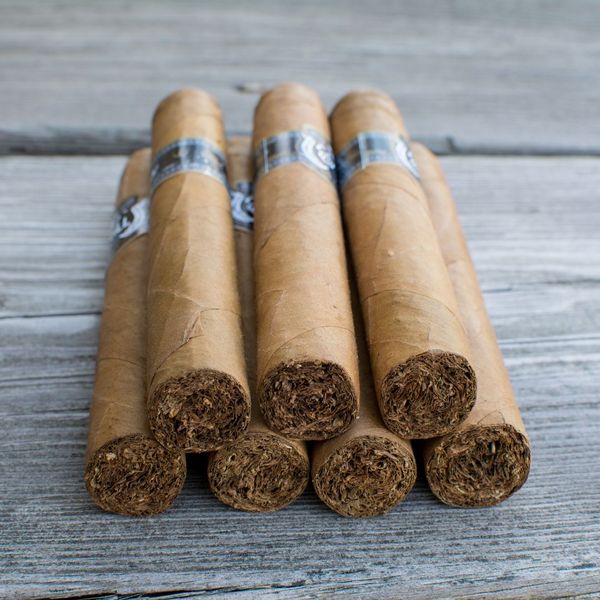 Six cigars stacked on a wooden surface