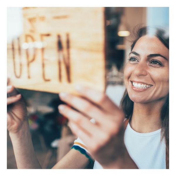 woman turning a business open sign