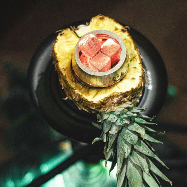 Hookah bowl topped with hot coals on pineapple