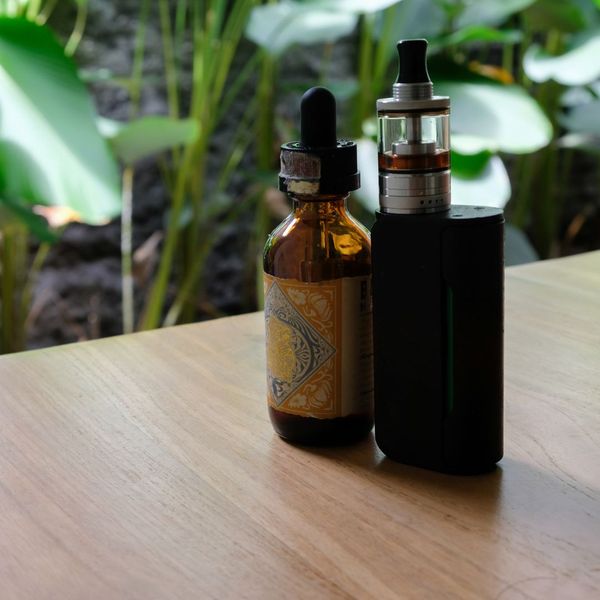 E-liquid bottle and vape mod on a wooden table