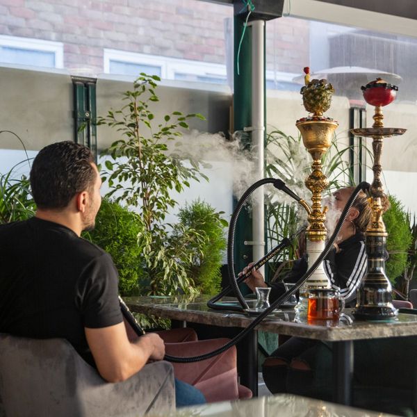 Two men smoking hookah at an outdoor lounge