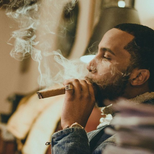 Man smoking a cigar, blowing thick smoke