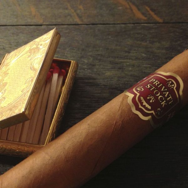 Cigar with matchbox on dark wooden table