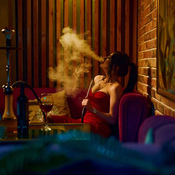 Woman in red dress smoking hookah indoors