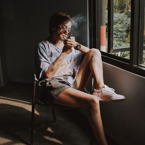 Woman smoking by a window.