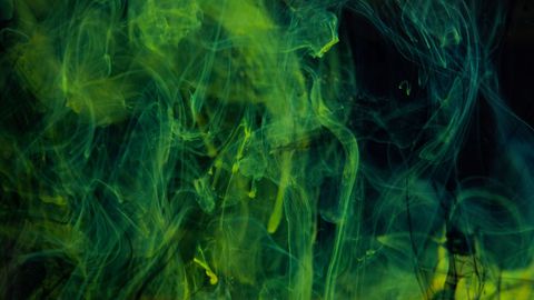 Swirling green smoke or ink in dark liquid background