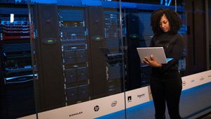 woman on a laptop in a server room woman on a laptop in a server room