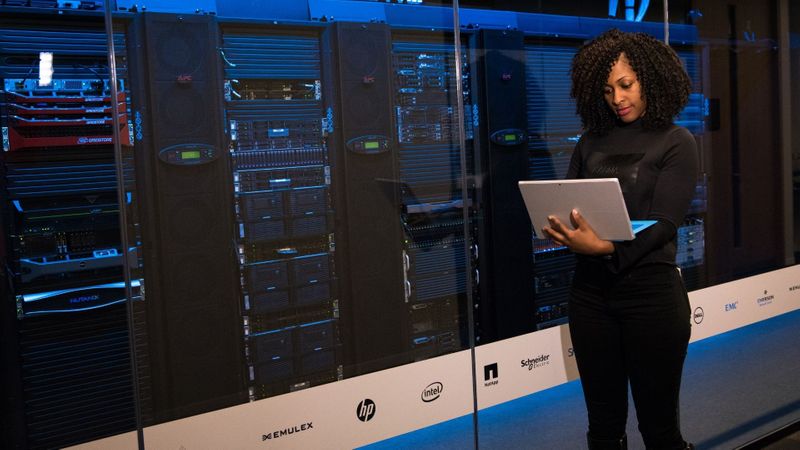 woman on a laptop in a server room woman on a laptop in a server room