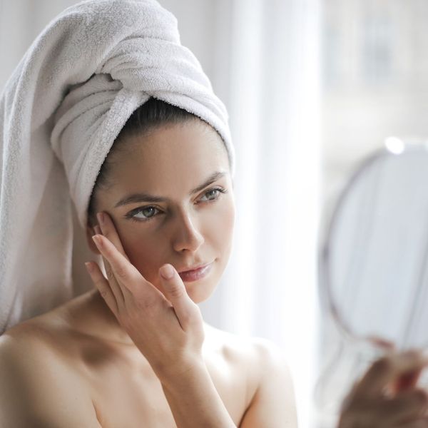 woman looking at skin in mirror