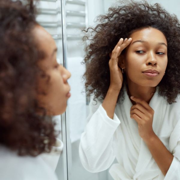 A woman looking at her skin in the mirror