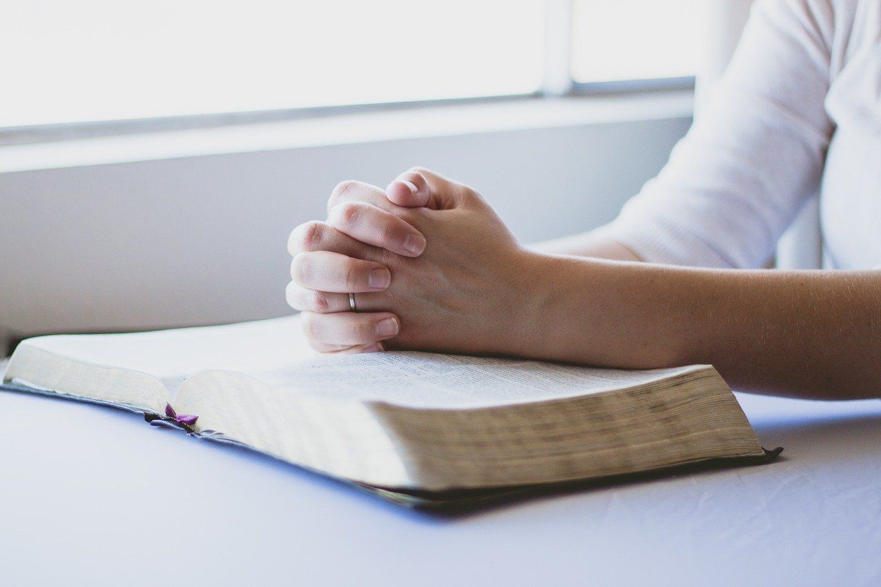 woman praying while studying bible