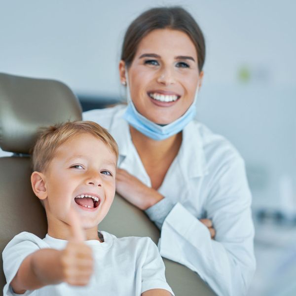 A friendly kids dentist with a child giving a thumbs up