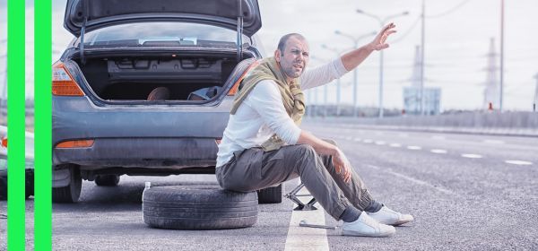 man waving for help next to broken down car