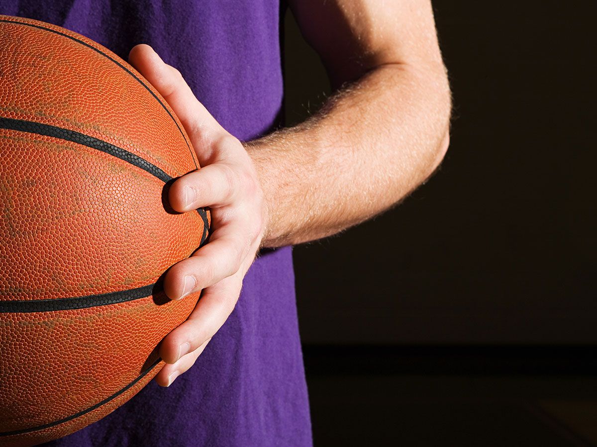 A person in a purple shirt holding a basketball. 