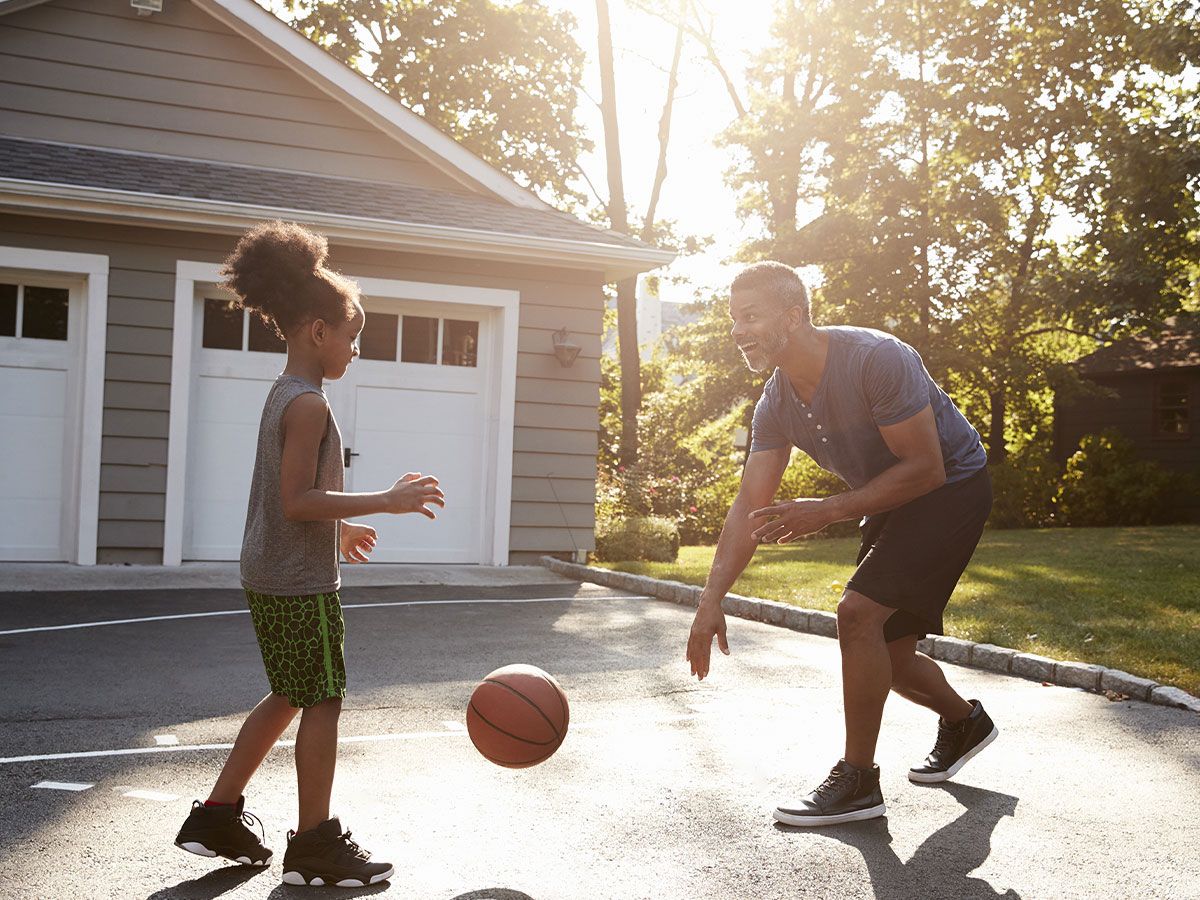 A man and a young child playing basketball together. 