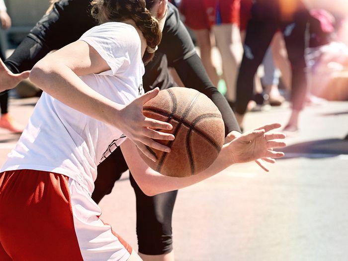  A young girl playing basketball outside. 