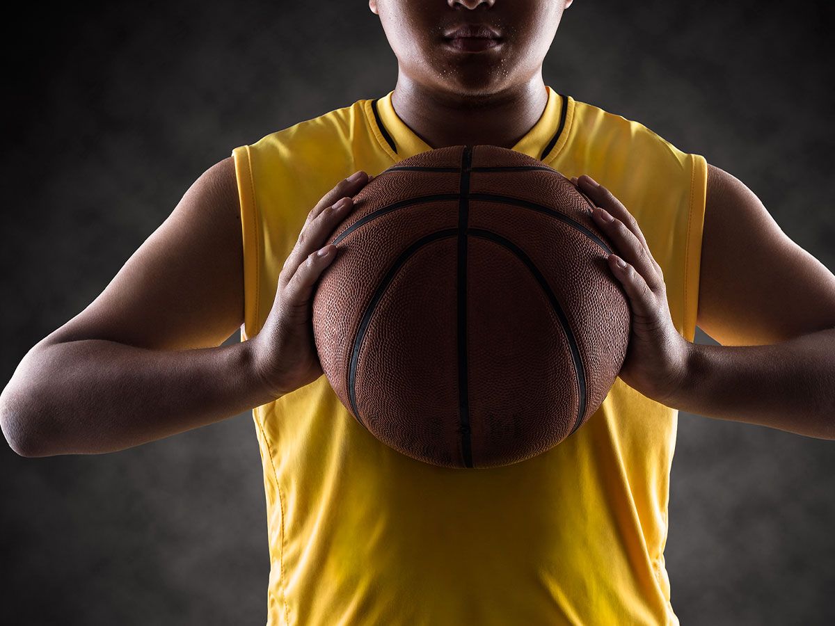 A person holding a basketball up to their chest.