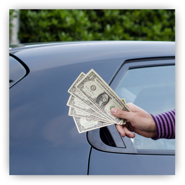 Handful of cash in front of a car