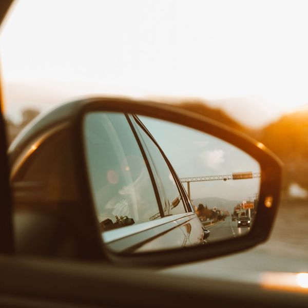 looking through rear view mirror at sunny road looking through rear view mirror at sunny road