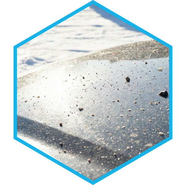 Intense winter sun glare reflecting off snow onto a car hood