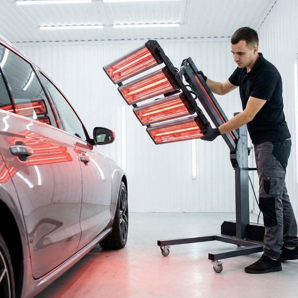 A professional detailer uses a modern infrared curing lamp to cure a ceramic coating.