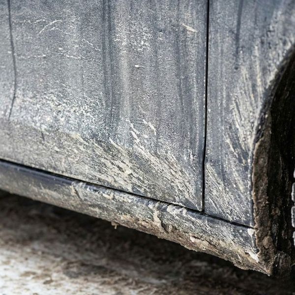 Close-up of a car covered in road salt and grime from winter driving.