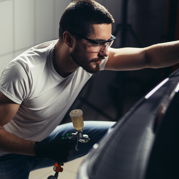 A person adding a coating to a car