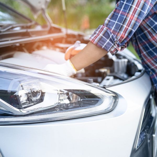driver sitting behind steering wheel technician working on car